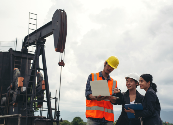 engineering-team-stands-beside-working-oil-pumps-with-sky